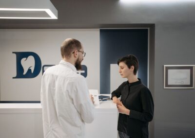 A male dentist consulting a female patient at a modern dental clinic reception.